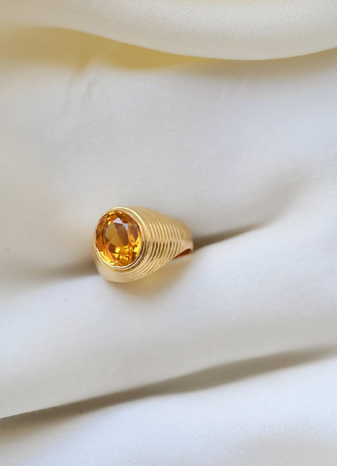 Vintage citrine pinky ring in 18K gold with ribbed dome, resting on ivory silk