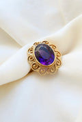 Antique amethyst filigree ring in 14K gold resting on ivory silk, the stone deep royal purple