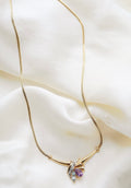 Vintage 14K gold necklace with amethyst, topaz and diamonds resting on ivory silk