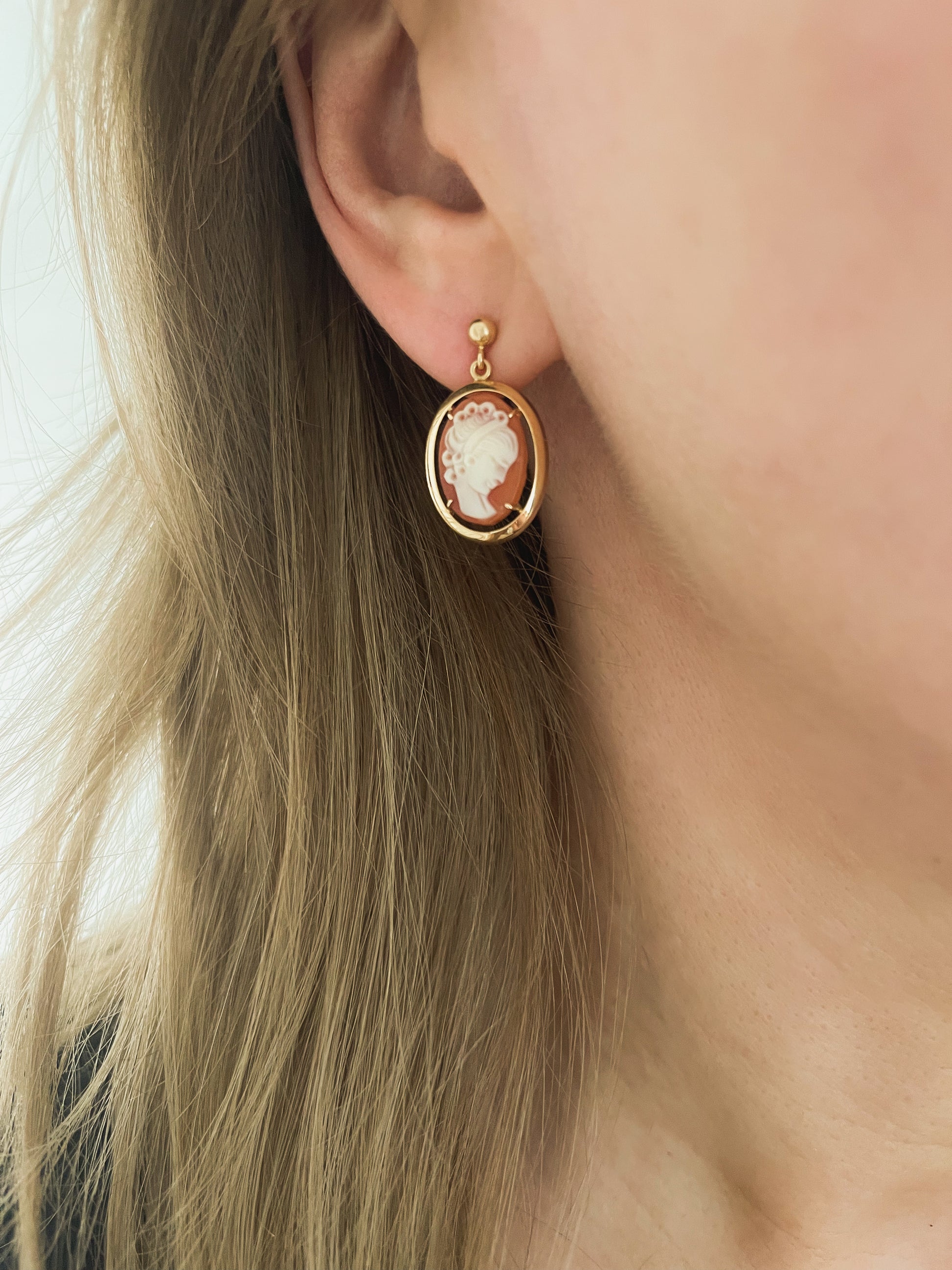 The antique cameo drop earring worn, swinging just below the ear