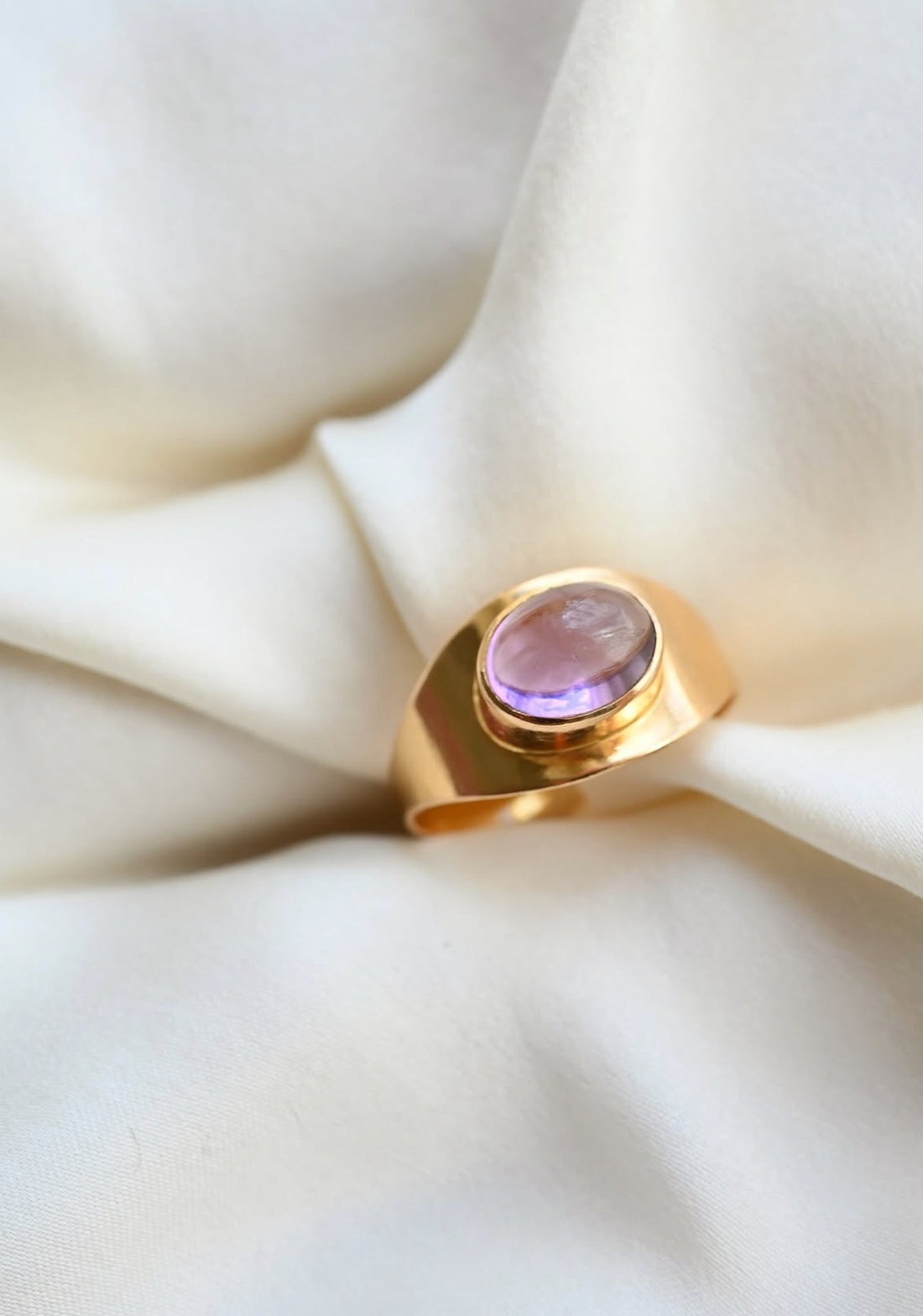 Modernist amethyst cabochon ring in 18K gold from Sweden 1961, resting on ivory silk