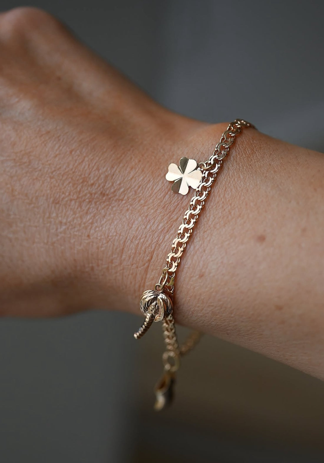 Vintage 18K gold charm bracelet with hearts, clover, shoe and palm tree charms on ivory silk