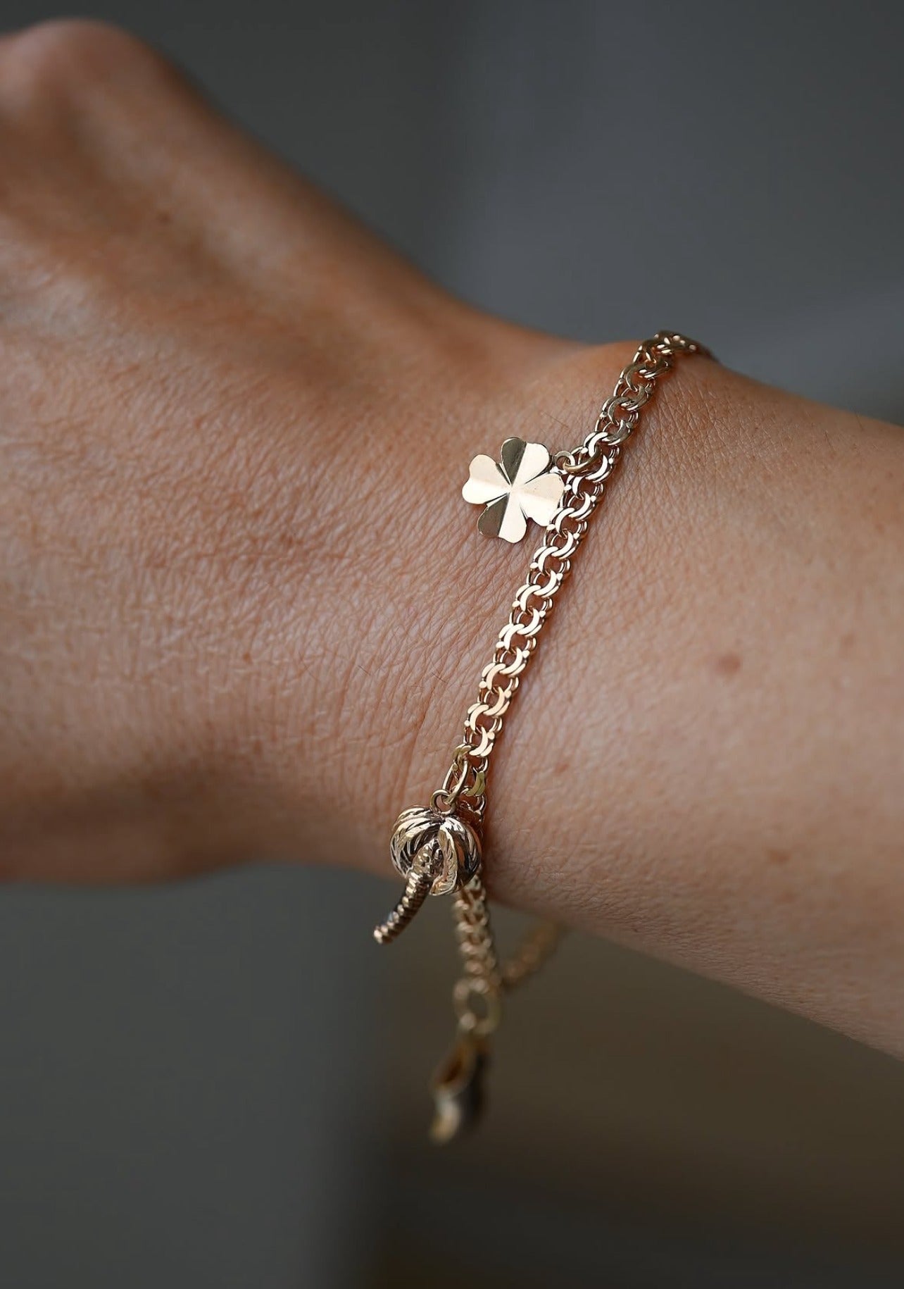 The lucky charm bracelet worn on the wrist, the clover catching the light