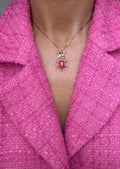 The cherry ruby bow pendant worn on a fine gold chain against a pink jacket