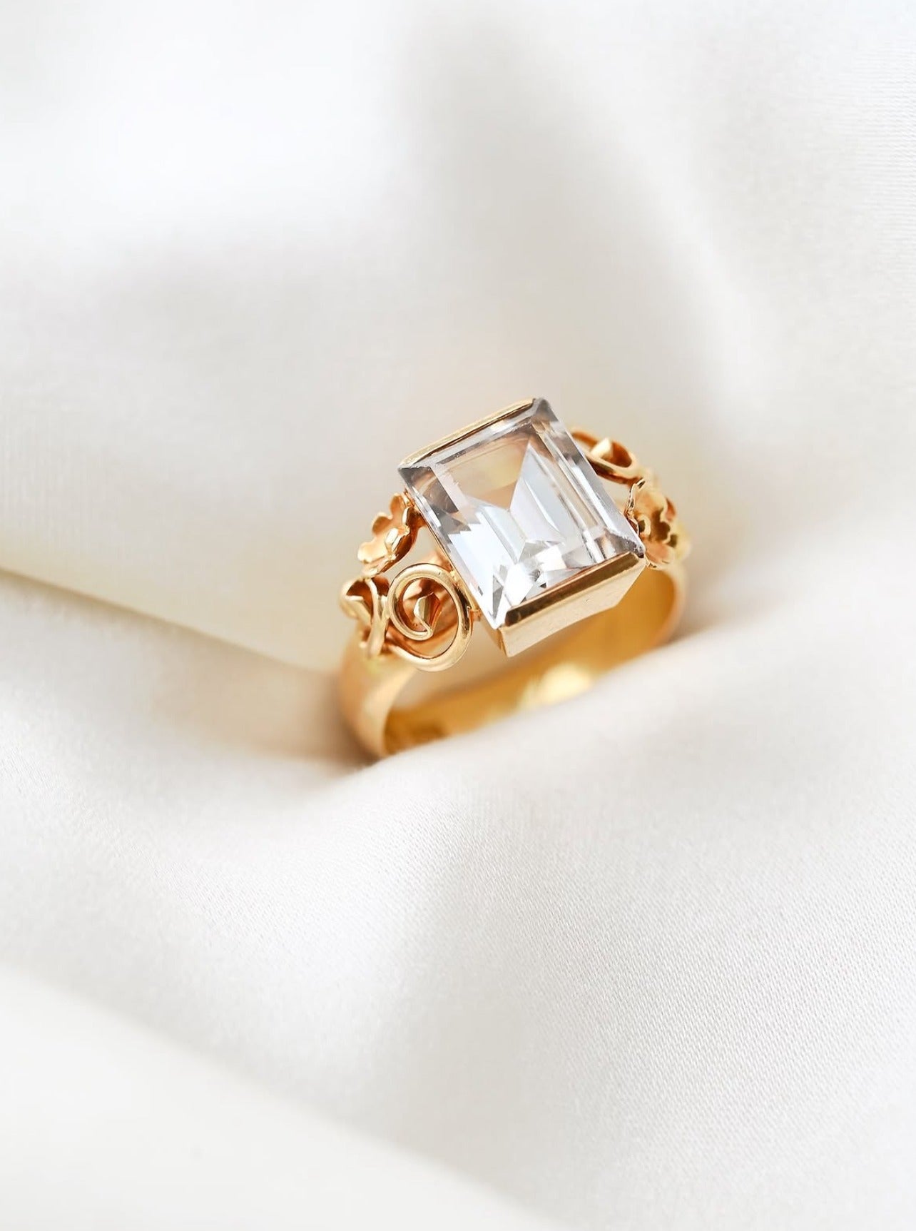 Romantic antique ring from 1896 with icy step cut rock crystal and golden flowers, on ivory silk
