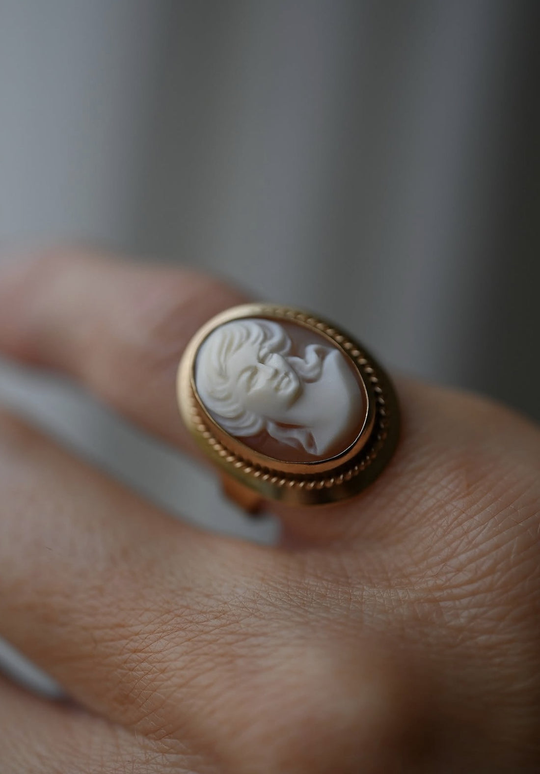 Vintage 18K gold cameo ring with twisted rope border resting on ivory silk