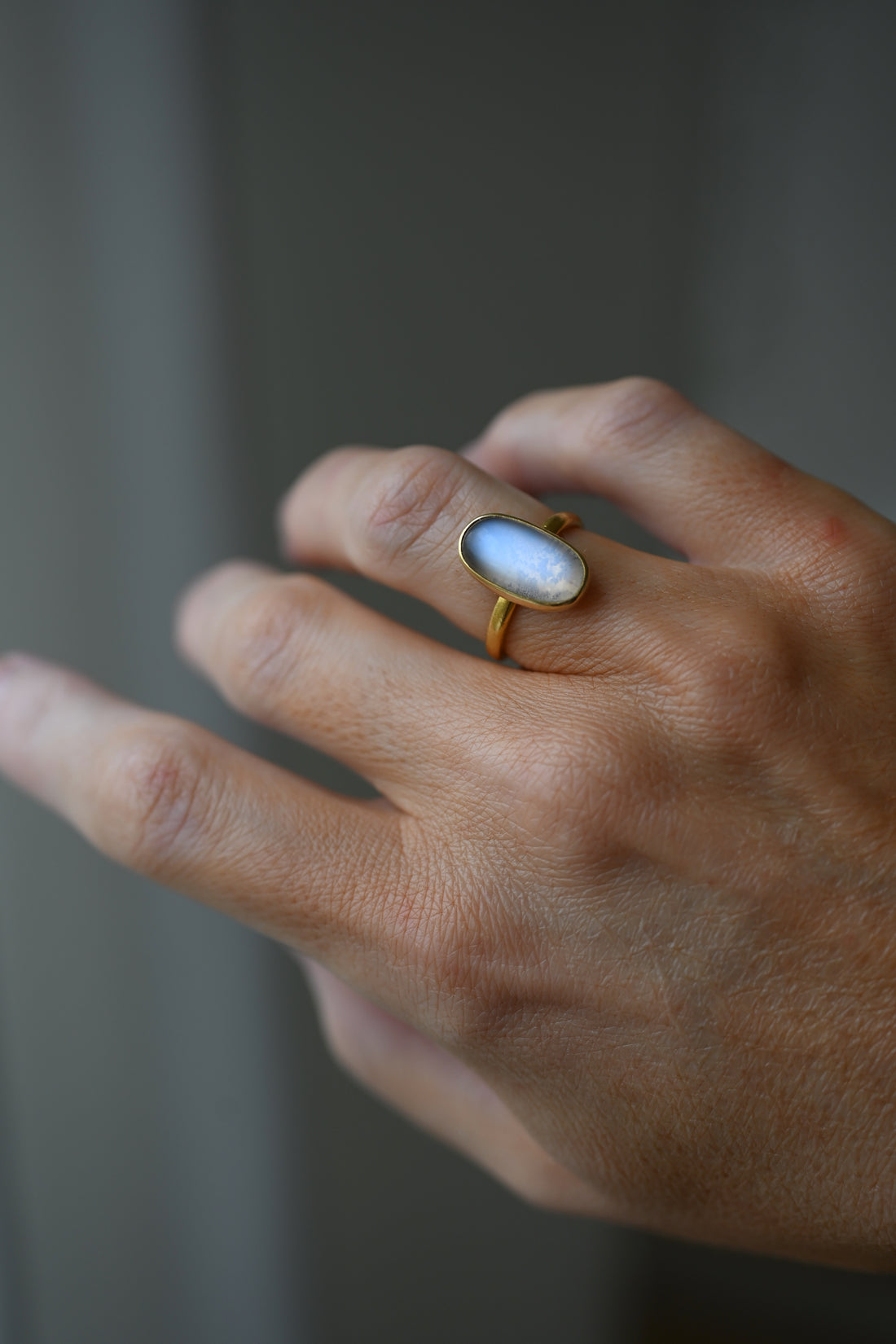 100 year old Swedish moonstone ring in 23K gold worn on the hand, the oval stone glowing blue