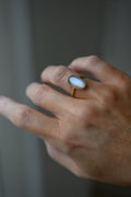 100 year old Swedish moonstone ring in 23K gold worn on the hand, the oval stone glowing blue