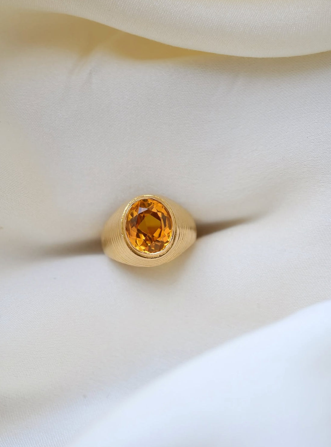 Vintage citrine pinky ring in 18K gold with ribbed dome, resting on ivory silk