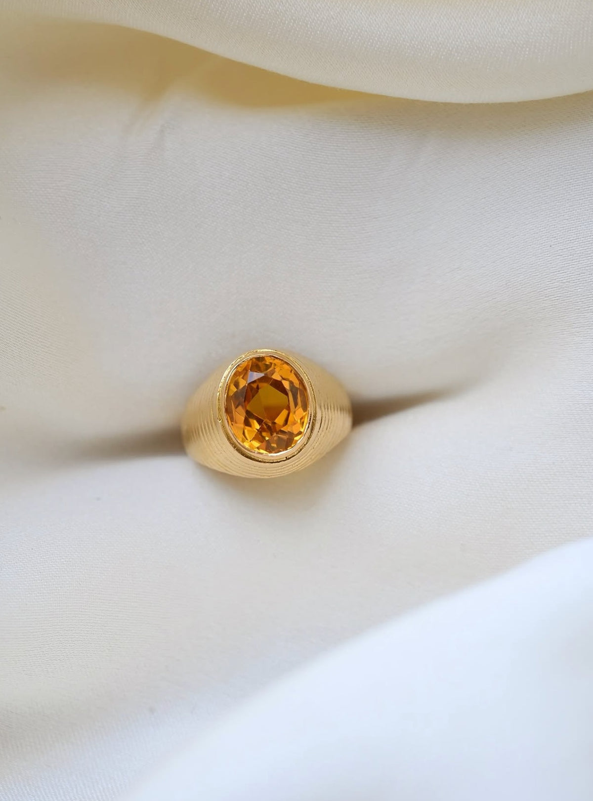 Vintage citrine pinky ring in 18K gold with ribbed dome, resting on ivory silk