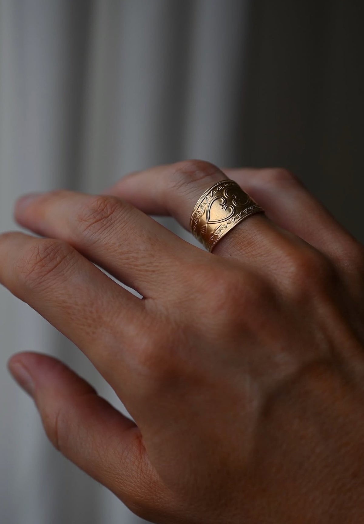 The heart cigar band worn on the hand, the stamped borders catching the light