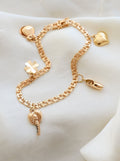 Vintage 18K gold charm bracelet with hearts, clover, shoe and palm tree charms on ivory silk