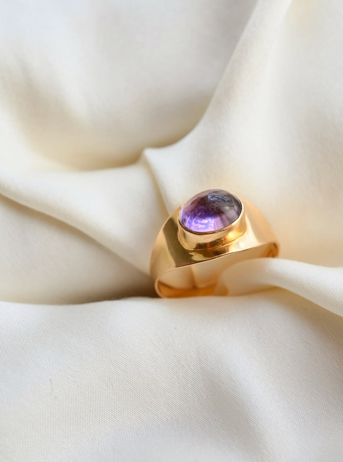 The violet cabochon glowing in its smooth bezel