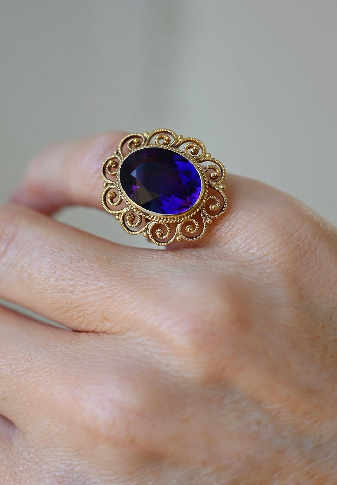 The amethyst glowing almost blue in the light, framed by handmade filigree spirals