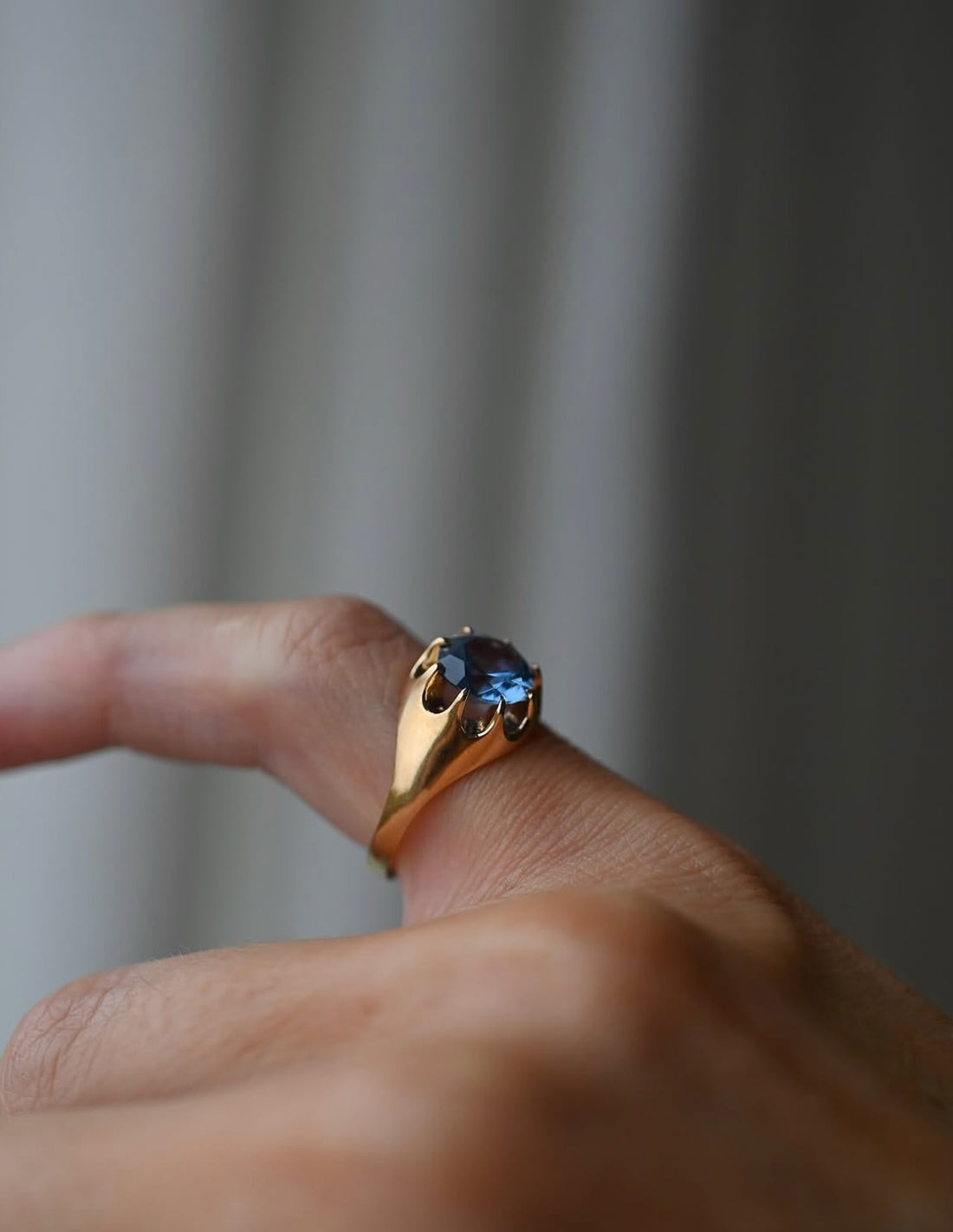 Antique 1922 Swedish ring with cornflower blue topaz in a claw setting, resting on ivory silk