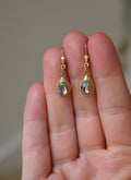 The spinel drop earrings held in the hand showing their soft sparkle