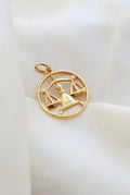 Vintage 18K gold Libra zodiac pendant with openwork scales, resting on ivory silk